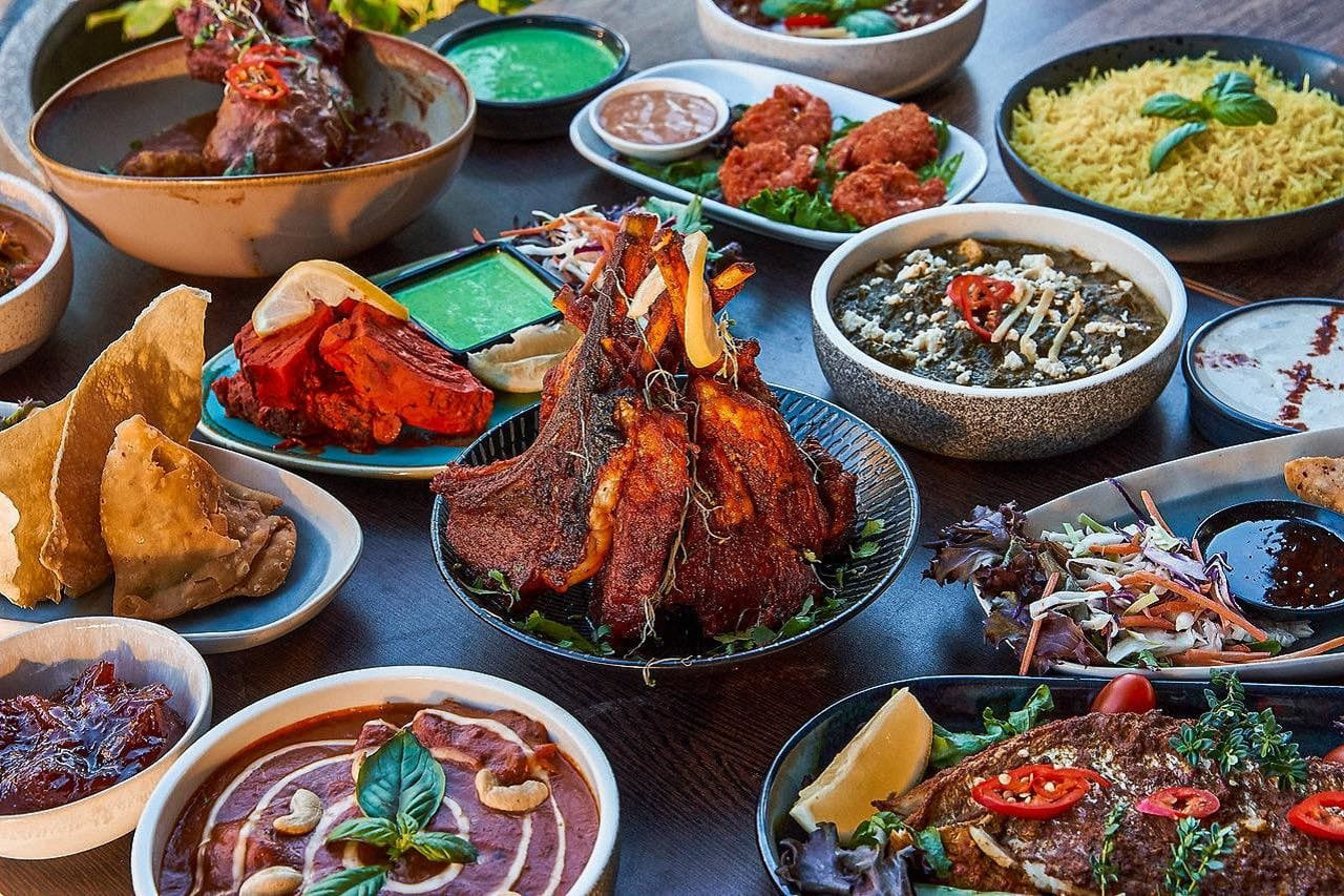 Large Indian food platter with curries rice and samosas