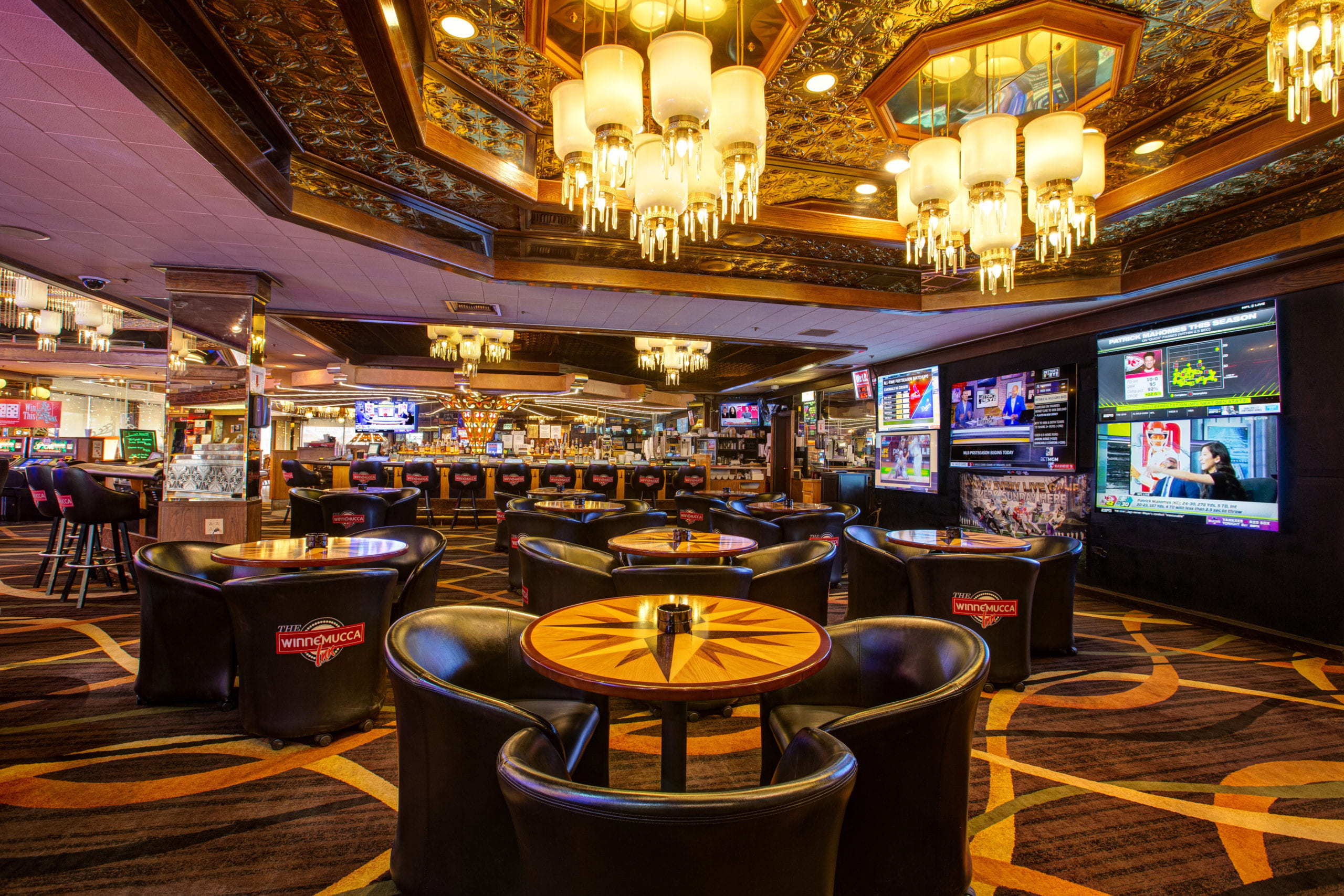 Sportsbook lounge with tables television screens and bar area